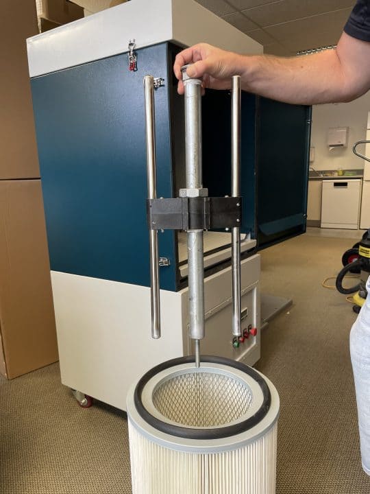 Pleated filter cartridge being lifted out of the welding smoke collector for cleaning or replacement
