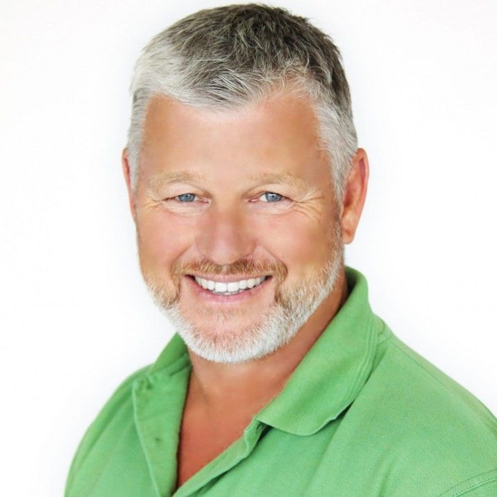 Smiling middle-aged man in a green polo shirt with grey hair and beard.